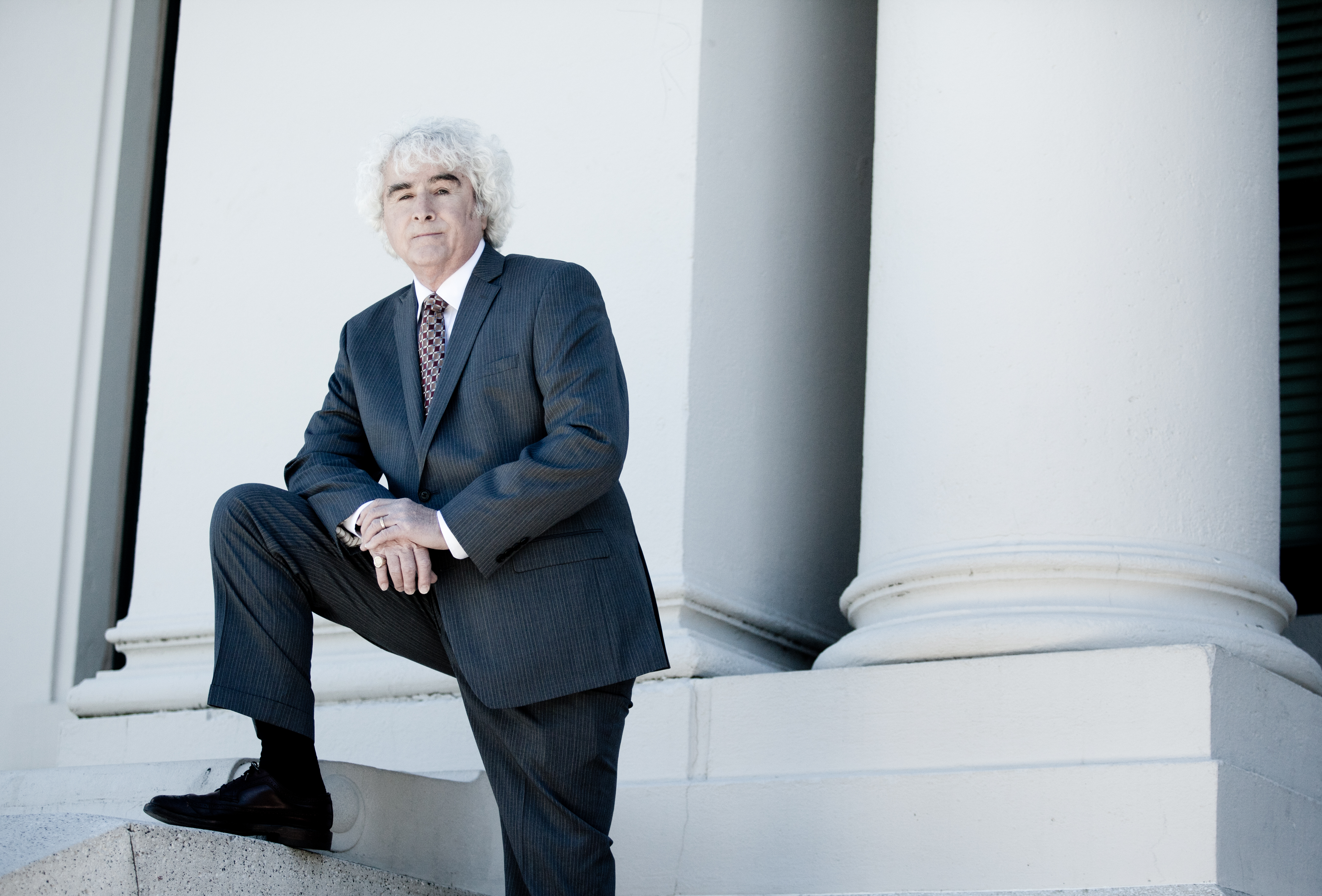 Daniel P. Sheehan seated beside the columns of a courthouse